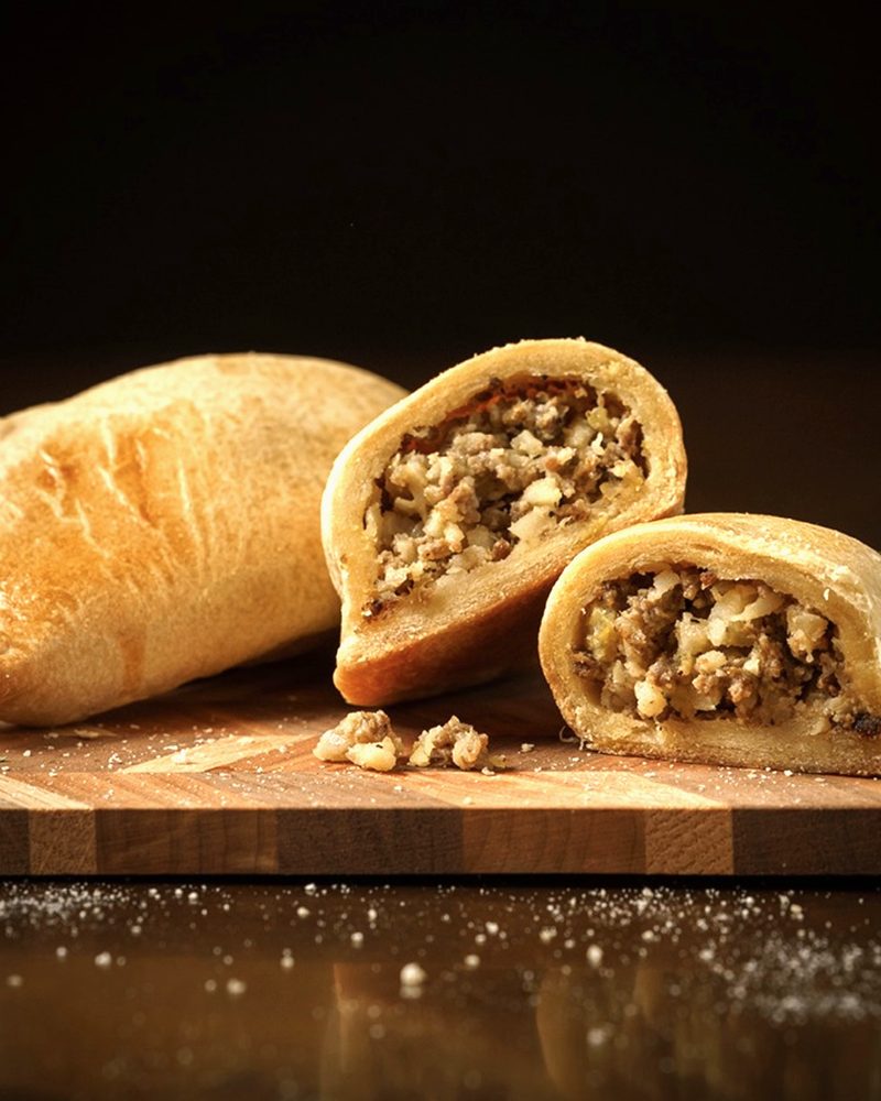 A mini meat pie cut in half, with the seasoned filling inside